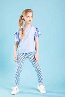 Mavi arka planda mavi elbiseli güzel bir kızın tam boy portresi..