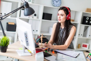 Genç bir kız bir masanın ayakta, yeşil kalem tutan ve ekrana bakarak. Önce kız masanın üzerinde manyetik bir pansiyondur. Kulaklıklar giyen kız kafasına.