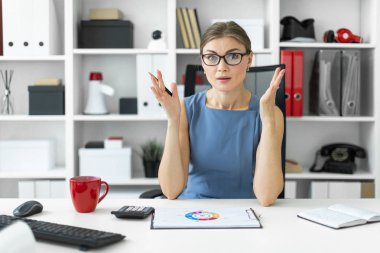 Genç bir kız ofiste bir masada oturur ve bir belgeyi içeren bir grafik görünüyor.