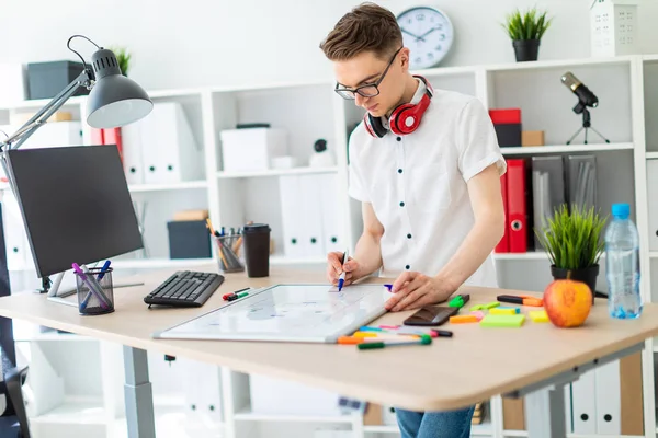 Genç bir adam beyaz bir gömlek ve ışık kot parlak bir ofiste çalışıyor. alan derinliği ile fotoğraf