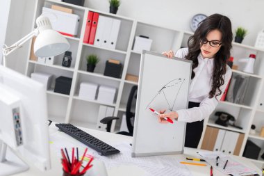 Güzel bir genç kız bir Ofis Masası standları ve manyetik bir işaretleyici manyetik tahtaya çizer.
