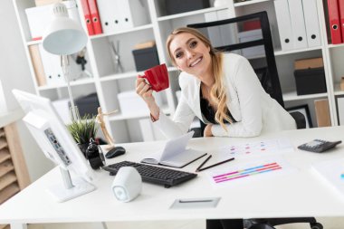 Genç bir kız ofiste bilgisayar masasında oturan ve bir holding. Kız masada daha önce diyagram olan.