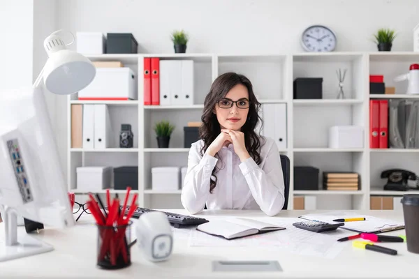 Schönes junges Mädchen sitzt am Tisch im Büro. — Stockfoto