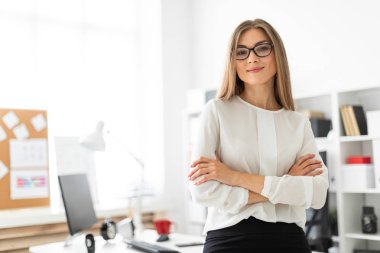 Genç bir kız ofiste bir masaya yaslanmış duruyor..