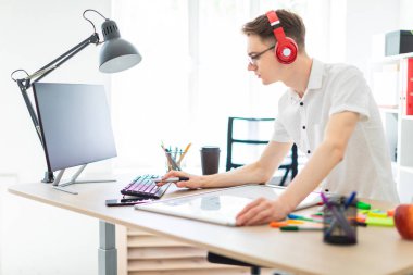 Bir genç adam gözlük ve kulaklık bilgisayar çalışıyor. Adam bir manyetik kurulu ve işaretleri olmadan.