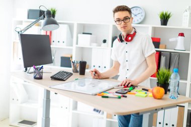 Gözlüklü genç bir adam bir bilgisayar masası duruyor. Genç bir adam bir işaretleyici manyetik bir tahtaya çizer. Çocuklar kulaklık boynuna asmak.