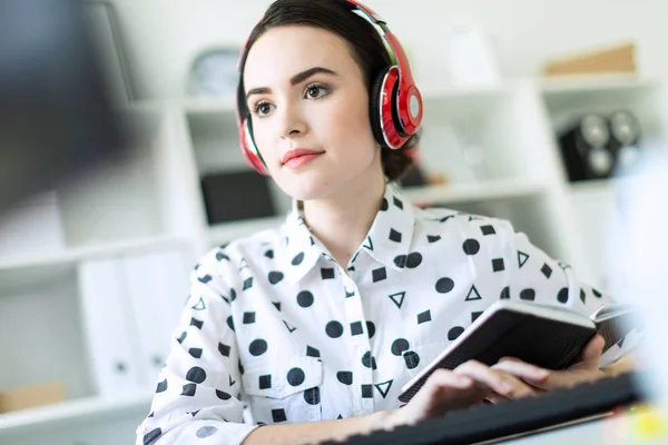 Mooie jonge meisje zit in de koptelefoon op balie in kantoor. Foto met scherptediepte, focus op meisje. — Stockfoto