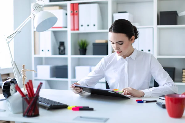 Uma jovem senta-se no escritório, segura uma caneta na mão e olha através de documentos . — Fotografia de Stock