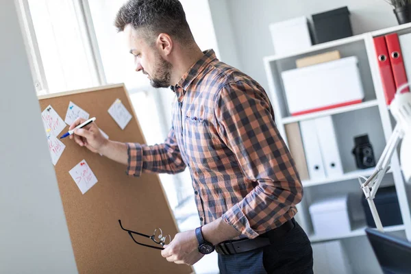 Bir adam ofis pencerenin yanında duruyor ve bir işaretleyici çıkartmaları yazıyor.