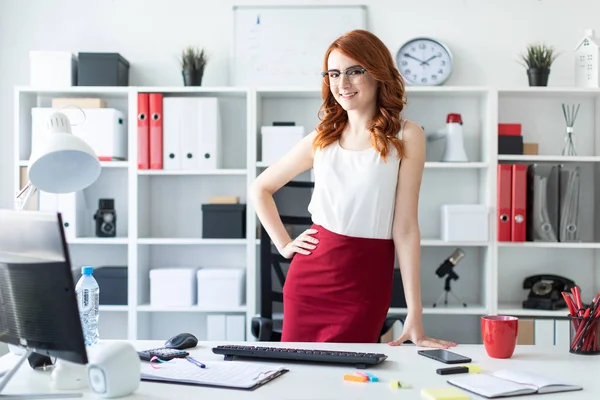 Güzel genç kız office tablo yakın duruyor. Kız bir yandan onun kalça üzerine koydu ve ikinci masanın üzerine eğildi.