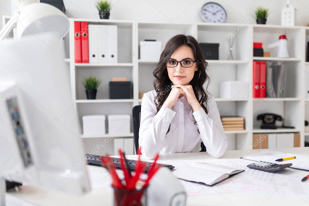 Beautiful young girl is sitting at the table in the office.