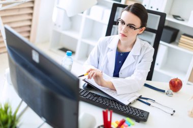 Beyaz bir elbise içinde güzel bir genç kız bir bilgisayar masası belgeler ve bir kalem ile onun elinde oturuyor.