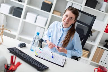 Genç bir kız ofiste bir masada oturur ve bir işaretleyici elinde tutan.