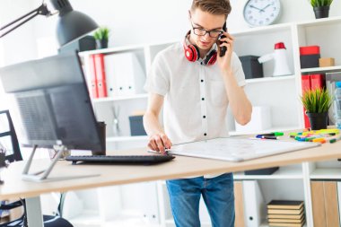 Gözlüklü genç bir adam bir bilgisayar masası duruyor ve telefonda konuşuyor. Önce onu bir manyetik kurulu ve işaretleri yatıyor. Çocuklar kulaklık boynuna asmak.