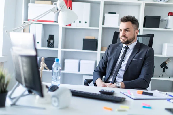 Bir adam masada ofiste bir sandalyede oturur ve ekrana görünüyor.