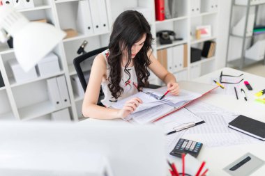 Güzel bir genç kız bir ofisinde oturur Resepsiyon onun elinde bir kalem düzenliyor ve başparmak aracılığıyla belgeleri içeren bir klasör.