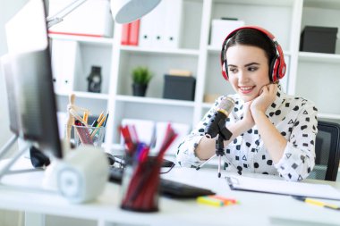 Kulaklık ve mikrofon ofis masada oturan ve konuşmak güzel genç kız.