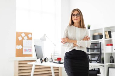 Genç bir kız ofiste bir masaya yaslanmış duruyor..