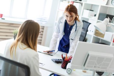 Beyaz bir elbise içinde güzel bir genç kız ofiste bilgisayar masası yanında duran ve muhatap ile iletişim. Kız notları belge içinde yapar..