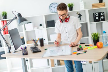 Genç bir adam beyaz bir gömlek ve ışık kot parlak bir ofiste çalışıyor. alan derinliği ile fotoğraf