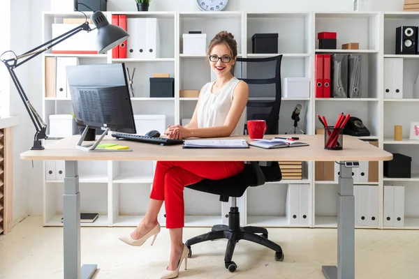 Uma jovem está sentada na mesa no escritório . — Fotografia de Stock