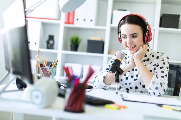 Kulaklık ve mikrofon ofis masada oturan ve konuşmak güzel genç kız.