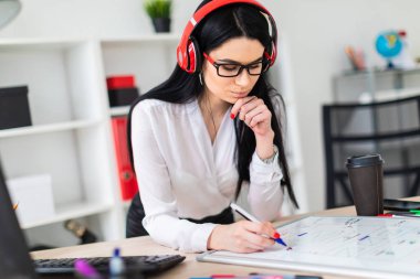 Genç bir kız kulaklık tablo anlamına gelir ve bir işaretleyici manyetik bir tahtaya çizer.