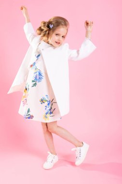 Pembe bir arka plan üzerinde poz ışık giysili bir genç kız.