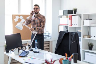 Bir adam ofis pencerenin yanında duran ve telefonda konuşurken.