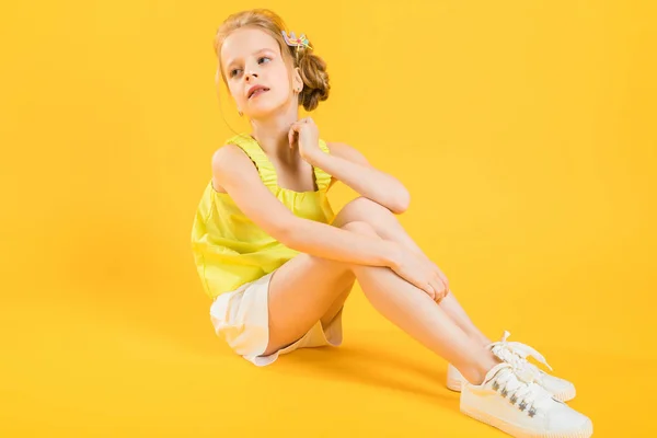 Una ragazza adolescente è seduta su uno sfondo giallo . — Foto Stock
