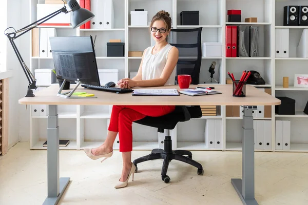 Seorang gadis muda duduk di meja di kantor . — Stok Foto