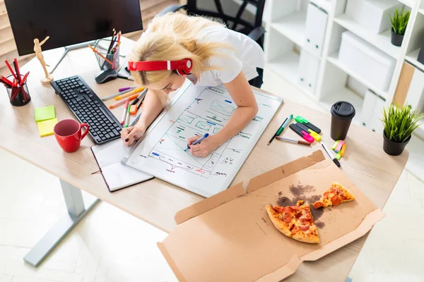 Uma jovem nos fones de ouvido fica perto da mesa e tem um marcador na mão. Na mesa está uma placa magnética . — Fotografia de Stock