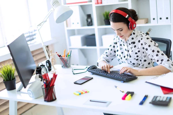Kulaklık Office masada oturan ve klavyede yazarak güzel genç kız.