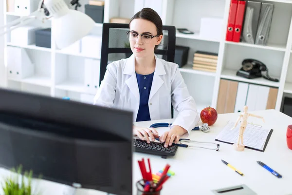 Beyaz bir elbise içinde güzel bir genç kız masada oturan ve klavyede yazarak.