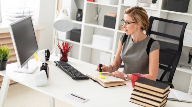 Genç bir kız, sarı bir işaret onun elinde tutan ofiste, bir masada oturuyor. Önce kız açık bir kitap yatıyor.