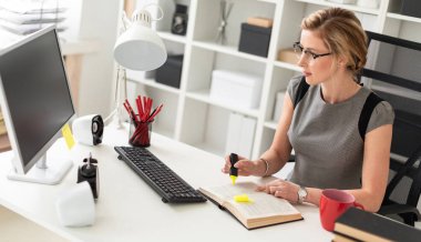 Genç bir kız, sarı bir işaret onun elinde tutan ofiste, bir masada oturuyor. Önce kız açık bir kitap yatıyor.