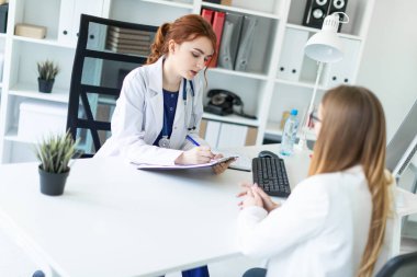 Beyaz bir elbise içinde güzel bir genç kız ofiste masada oturan ve muhatap ile iletişim. Kız notlar sayfasında yapar..