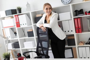 Ellerinin üzerinde sandalye ile ofiste, bir tabloda yakınındaki bir genç kız duruyor.