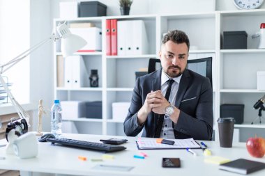 Bir adam masada ofiste bir sandalyede oturuyor.