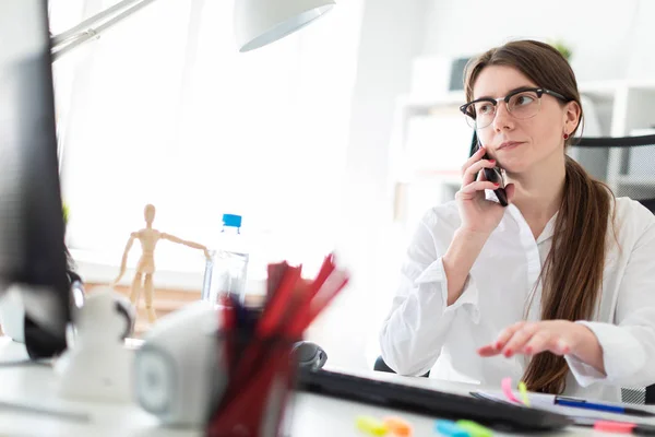 Ung flicka sitter vid skrivbord i office, prata på telefon och arbeta med dokument — Stockfoto