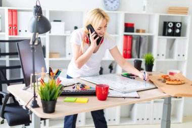 Genç bir kız bir masanın ayakta, telefonda konuşurken ve bir işaretleyici elinde tutan. Masaya manyetik bir pansiyondur. Kızlar kulaklık boynuna asmak.