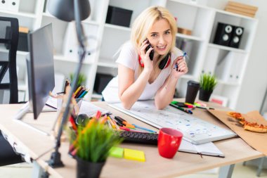 Genç bir kız bir masanın ayakta, telefonda konuşurken ve bir işaretleyici elinde tutan. Masaya manyetik bir pansiyondur. Kızlar kulaklık boynuna asmak.
