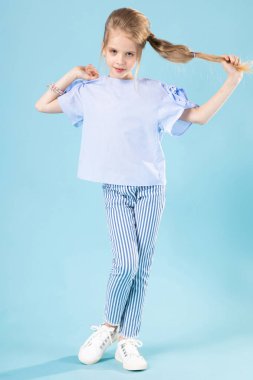 Mavi arka planda mavi elbiseli güzel bir kızın tam boy portresi..