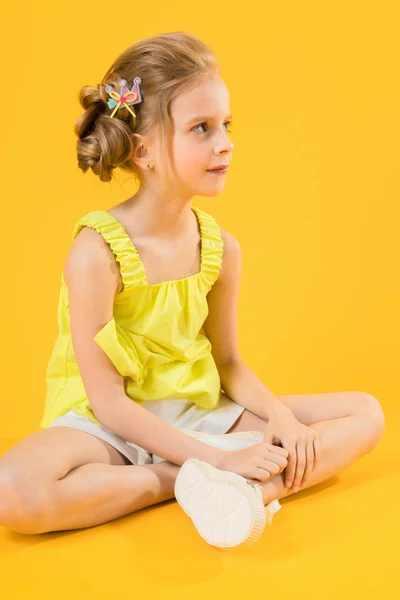 Ein Teenager-Mädchen sitzt auf gelbem Hintergrund. — Stockfoto