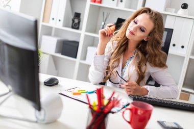 Güzel bir genç kız ofiste bir sandalyede oturur ve onu el gözlük ve turuncu bir işaret tutar.