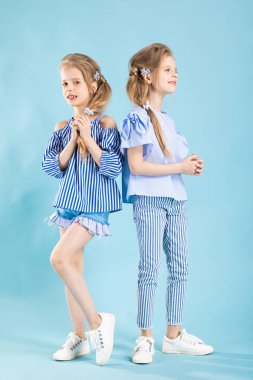 Mavi bir arka plan üzerinde kız ikiz ışık mavi giysiler içinde poz.