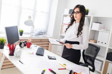 Güzel bir genç kız bir ofis masası anlamına gelir ve bir defter ve bir kalem tutan eline.