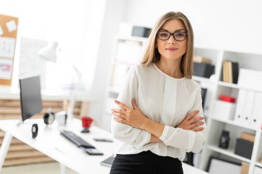 Genç bir kız ofiste bir masaya yaslanmış duruyor..