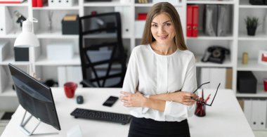 Genç bir kız ofiste bir tabloda yaslanmış ve gözlük onun elinde tutan duruyor.