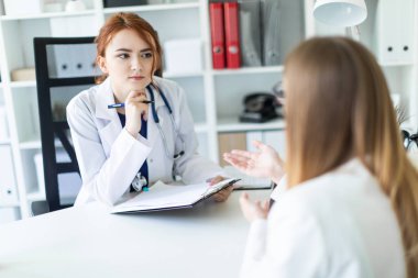 Beyaz bir elbise içinde güzel bir genç kız ofiste masada oturan ve muhatap ile iletişim. Kız notlar sayfasında yapar..